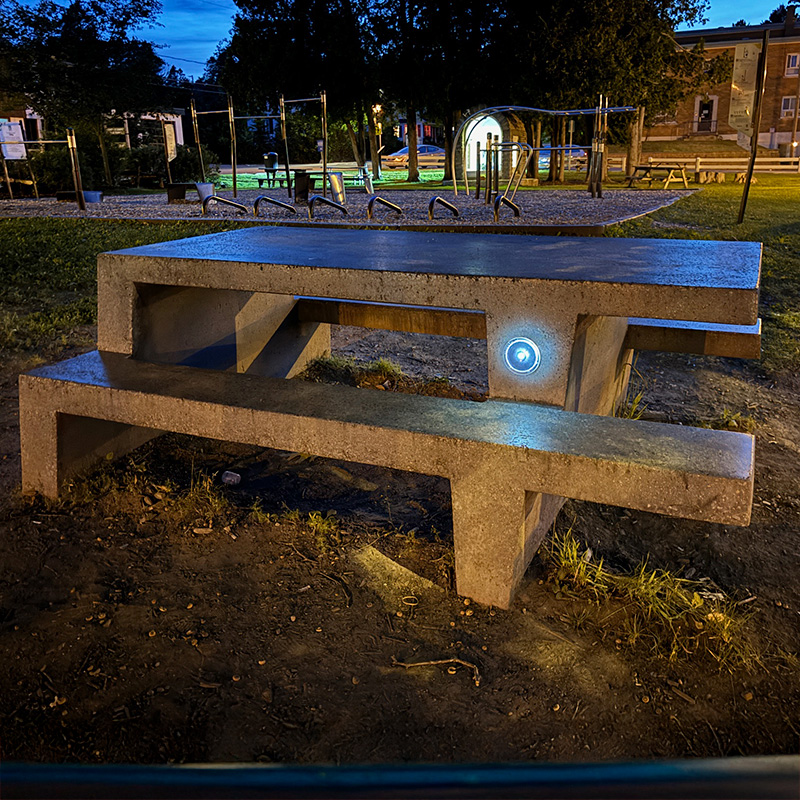 Jansen Concrete picnic table illuminated with LED light feature in evening park setting.
